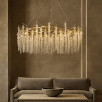 A modern living room features the Albero Crystal Chandelier by Morsale.com, its gold branches and crystals cascading above a neutral sofa and a wooden coffee table with a decorative bowl.