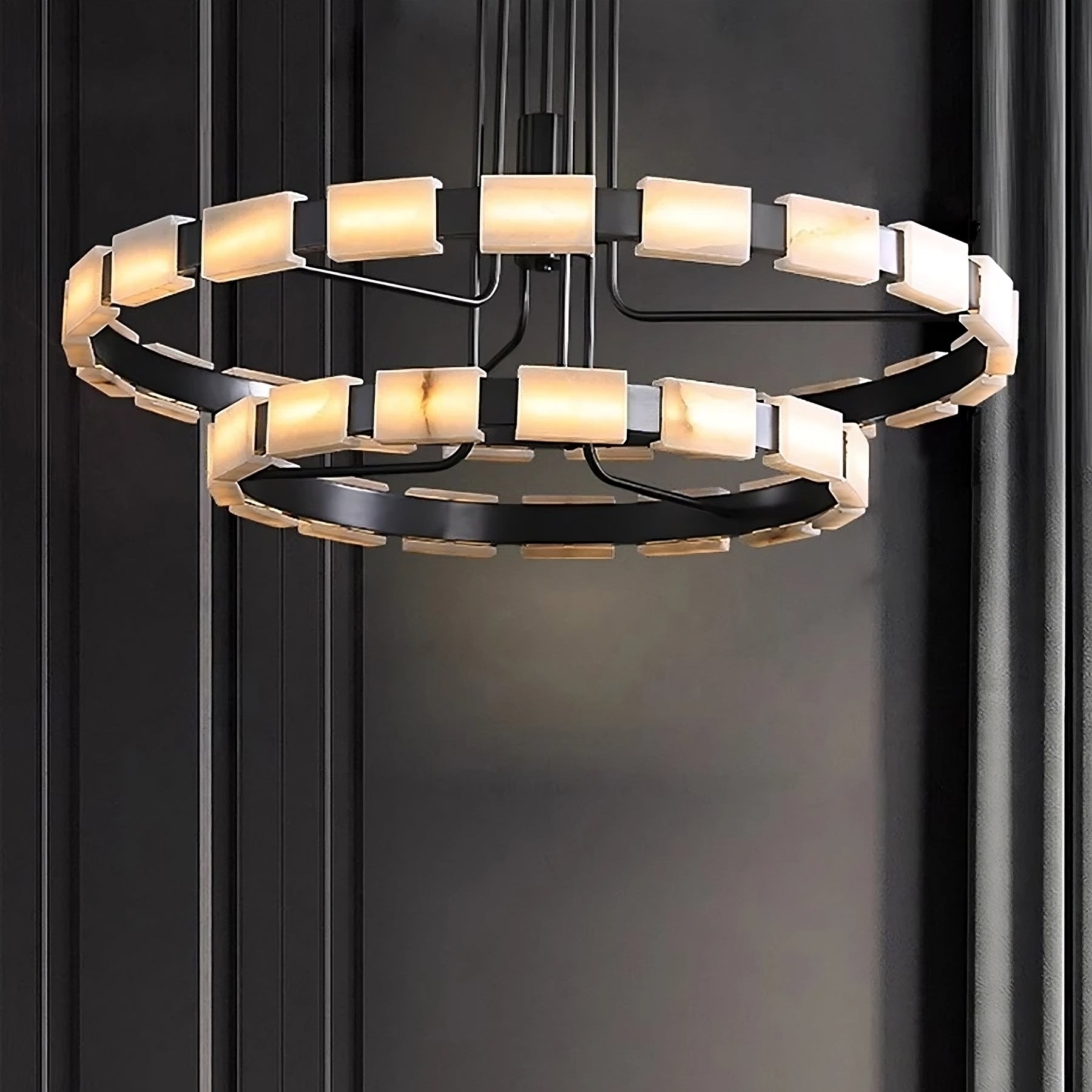 A modern chandelier with a black metal frame featuring two circular tiers adorned with rectangular frosted light panels. The Morsale.com Villa Marble Mid-Century Modern Chandelier's geometric design contrasts against a sleek, dark wall, creating a sophisticated and contemporary look.
