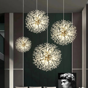 A modern living room features dark walls, a large piece of artwork depicting a sculpture of a head, and stylish furniture including a sofa, chairs, and a coffee table. Four El Sol Crystal Dandelion Lighting Fixtures by Morsale.com hang from the ceiling, illuminating the space elegantly with their K9 Crystals and LED Bulbs.