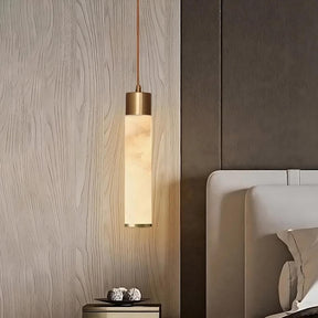 A modern bedroom features a minimalist design with light wood-paneled walls. The Moonshade Natural Marble Pendant Light Fixture by Morsale.com hangs next to a cushioned bed. On a small bedside table below are two decorative spheres.