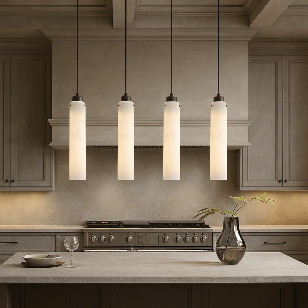A modern kitchen features beige cabinets, a stainless steel stove, four Morsale Noir Marble Pendant lights above the counter, a glass vase with greenery, and an empty wine glass on the countertop.