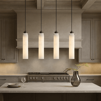 A modern kitchen features beige cabinets, a stainless steel stove, four Morsale Noir Marble Pendant lights above the counter, a glass vase with greenery, and an empty wine glass on the countertop.