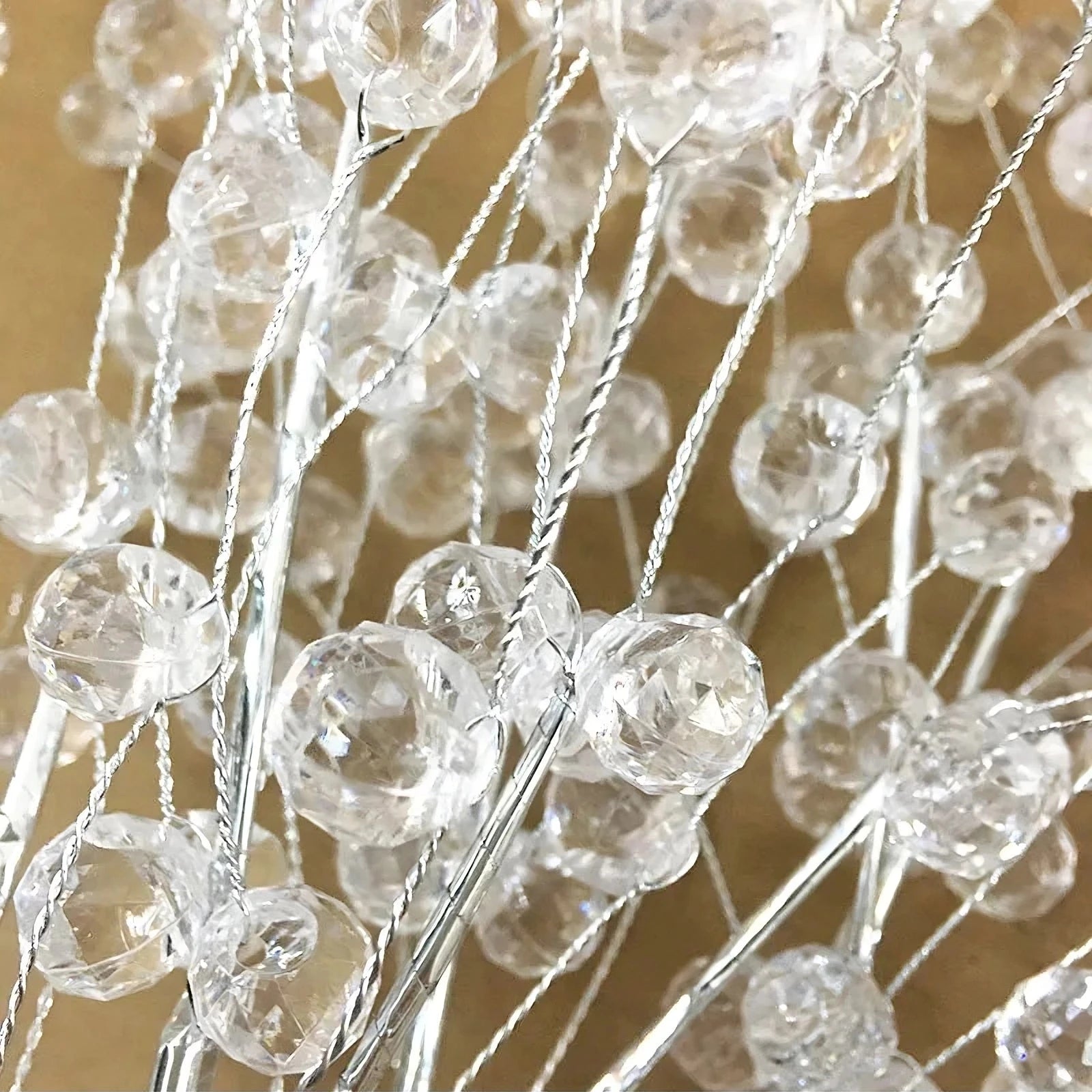 Close-up of numerous clear acrylic beads attached to thin, shimmering silver wires. The beads are round and faceted, creating a sparkling effect as they catch the light. Reminiscent of foil-wrapped branches, the text "Astra 35" Spark Ball Pendant Lighting Fixture by Morsale.com" appears at the bottom of the image.