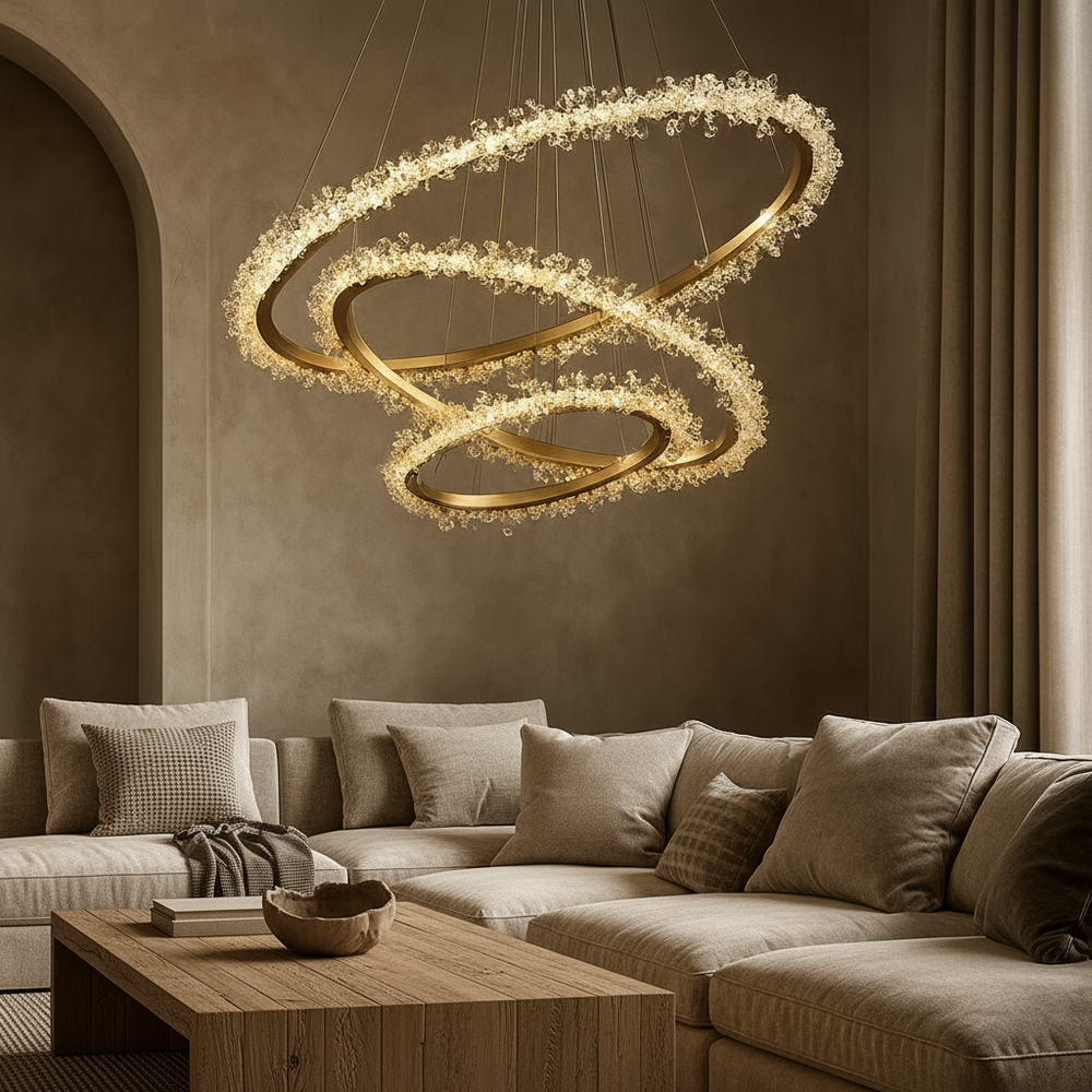 A modern living room with beige furniture and textured cushions is illuminated by the Capri 3-Ring Modern Chandelier from Morsale.com, its handmade crystals sparkling above a wooden coffee table to create a cozy, elegant atmosphere in warm neutral tones.
