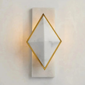 The Natural Marble Contemporary Wall Sconce Light showcases a gold-framed, diamond-shaped design crafted from natural marble. Light softly illuminates from behind the diamond, casting a warm glow on the wall. Its base is a simple rectangular piece that matches the material of the diamond, exuding art deco glamor.