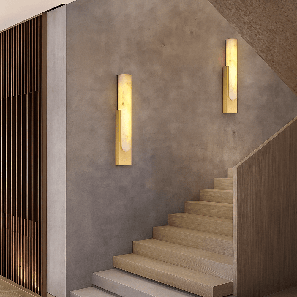 
                  
                    A modern indoor staircase with light wood steps, taupe walls, and two Wexford Marble Wall Sconces by Morsale.com emitting warm light. Vertical wooden slats accent the adjacent left wall.
                  
                