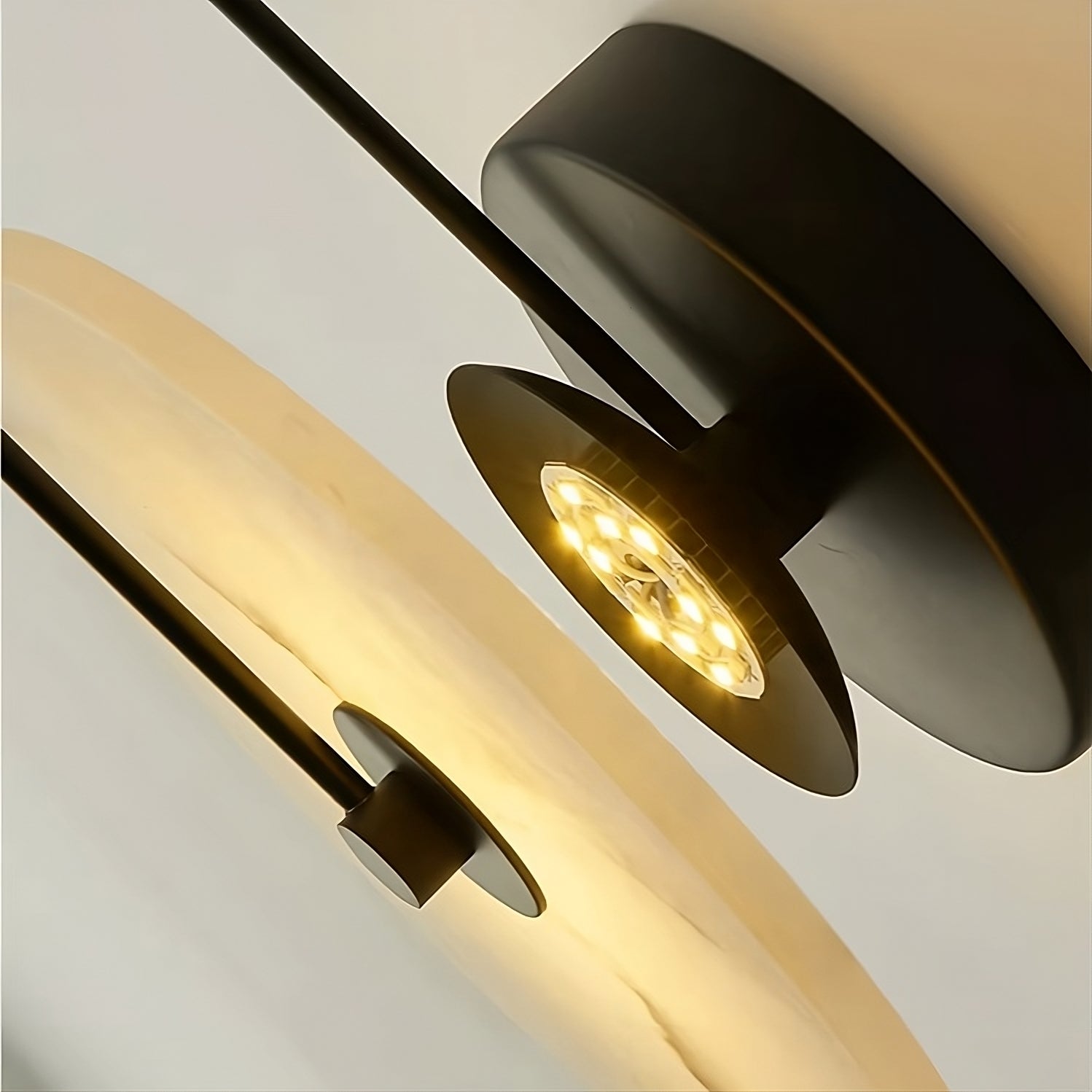 Close-up of the Moonshade Natural Marble Sconce Light by Morsale.com, showcasing two modern ceiling lamps with round shades and black stems, featuring warm white LED lights. The sleek, minimalistic design enhances home decor elegance against a light background.