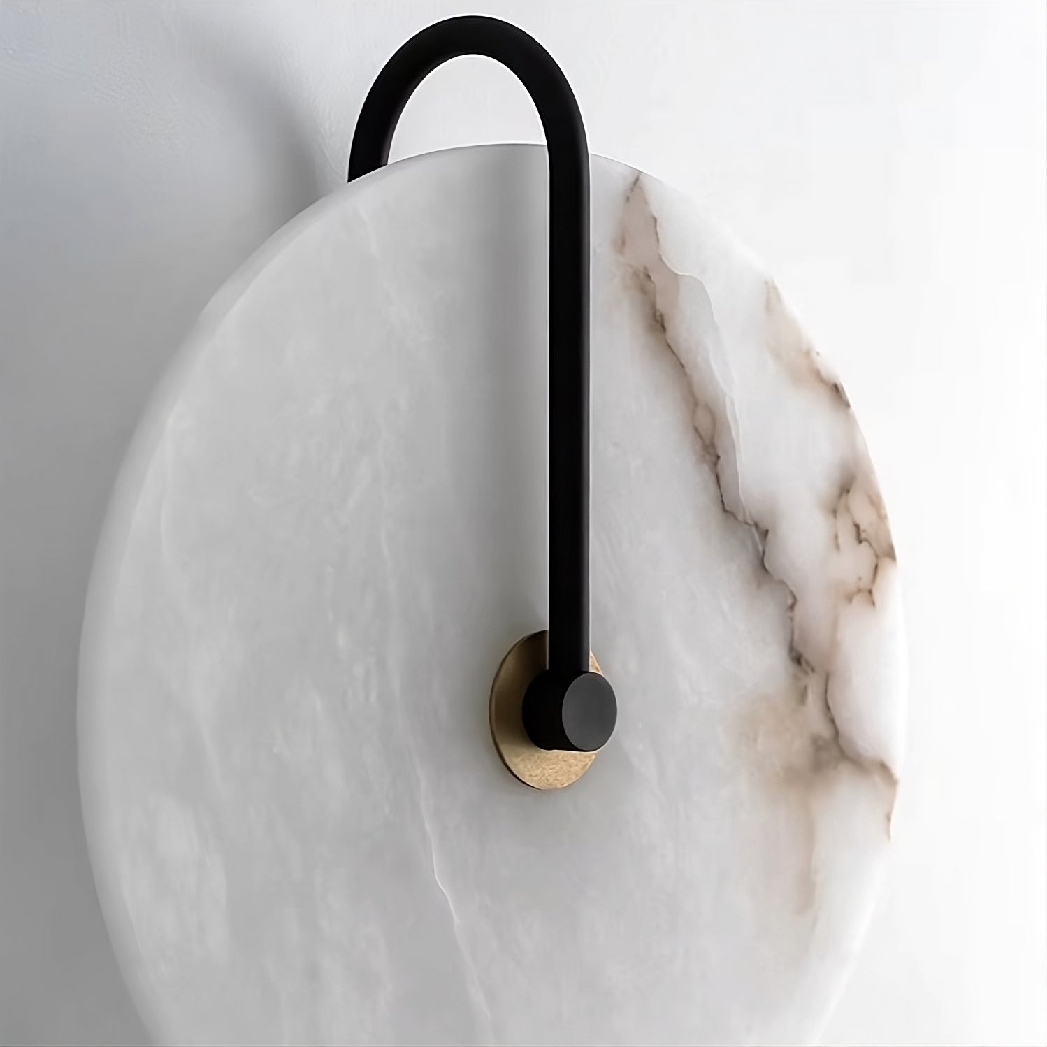 Introducing the Moonshade Natural Marble Sconce Light by Morsale.com: This circular sconce showcases natural marble with a white base and brown veining, elegantly complementing your home decor. The black, curved handle is gracefully attached to a golden mount, exuding sophistication against any plain white wall.