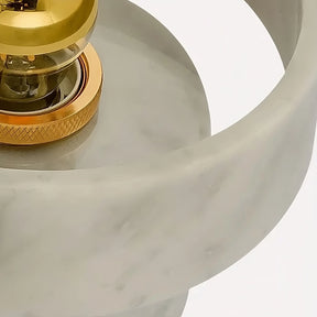 Close-up of a Morsale.com Moonshade Natural Marble Wall Light Fixture with a circular design. The lamp features a brass socket and a clear bulb, housed within a smooth, marble-like gray ring showcasing its unique texture marble sconce, all against a plain white background.