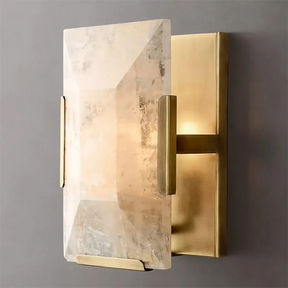 The Villano Calcite Crystal Wall Sconce by Morsale.com features a modern design with a rectangular brass base paired with a large, translucent, irregularly-shaped handcrafted crystal light cover. The internal light emits a soft, warm glow that beautifully illuminates the facets of the crystal. This elegant design adds an element of sophistication perfect for any interior decor.