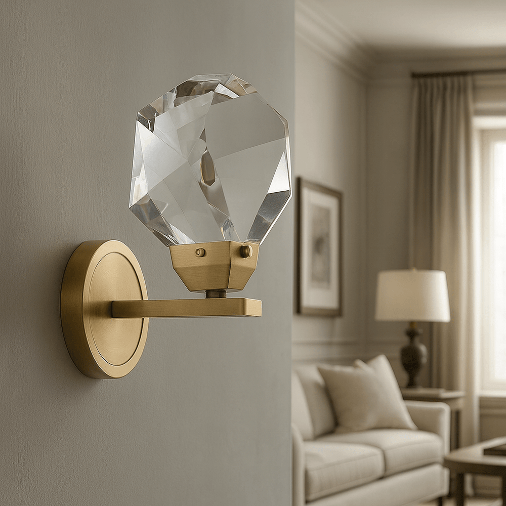 The Bari Crystal Sconce by Morsale.com features a brushed brass finish and a large faceted crystal shade, adding handcrafted elegance to living rooms with neutral decor, sofas, framed art, and curtained windows.