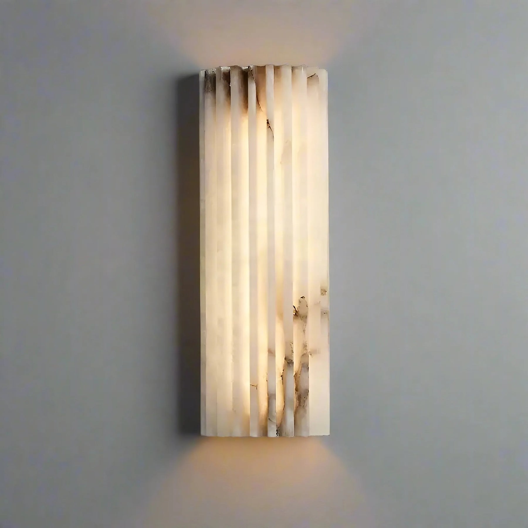 The Morsale Natural Marble LED Wall Sconce showcases a textured cylindrical design made from translucent marble, providing an elegant, warm glow against the gray textured wall.