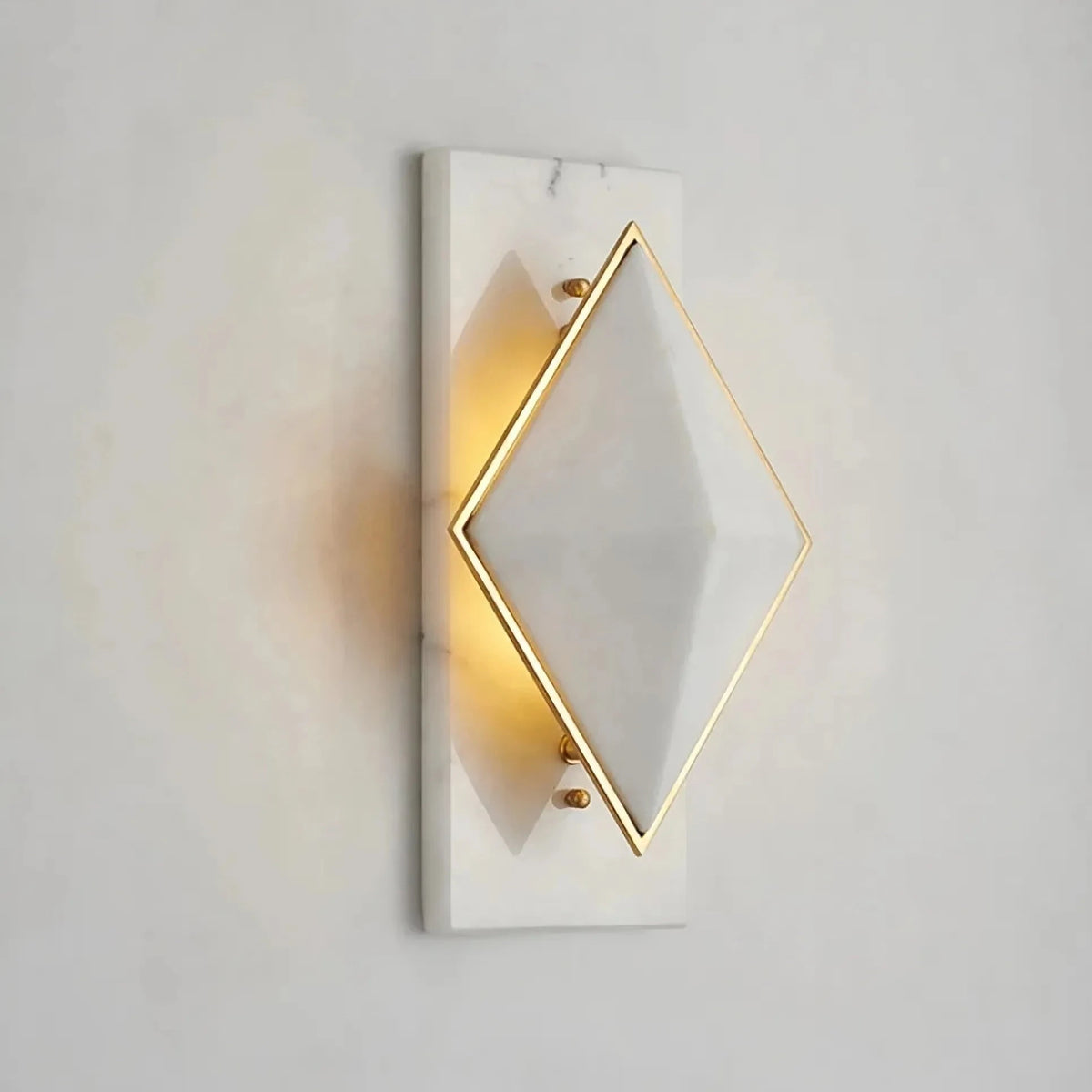 The Bigman Natural Marble Contemporary Wall Sconce Light features a modern geometric design. This sophisticated sconce boasts a diamond-shaped white shade with elegant gold trim, mounted on a sleek rectangular white marble base. It emits a warm glow, effortlessly adding elegance to any simple background.