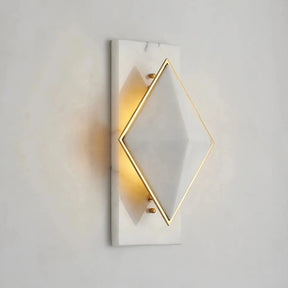 The Bigman Natural Marble Contemporary Wall Sconce Light features a modern geometric design. This sophisticated sconce boasts a diamond-shaped white shade with elegant gold trim, mounted on a sleek rectangular white marble base. It emits a warm glow, effortlessly adding elegance to any simple background.