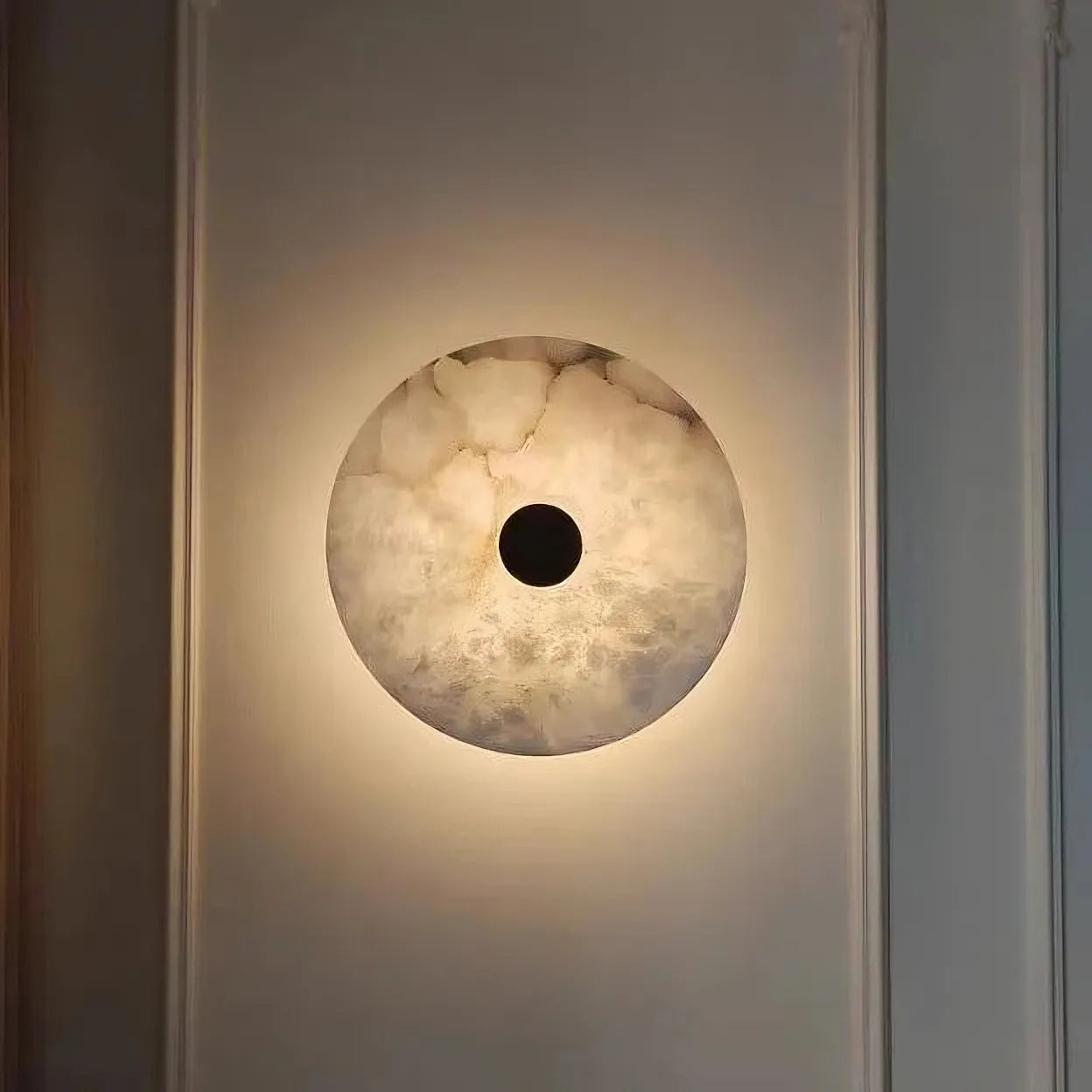 The Morsale Witney Copper & Marble Wall Sconce casts a warm glow with its marble-like pattern and dark circular center, combining modern style lighting with minimalist elegance.