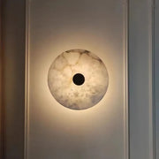 The Morsale Witney Copper & Marble Wall Sconce casts a warm glow with its marble-like pattern and dark circular center, combining modern style lighting with minimalist elegance.