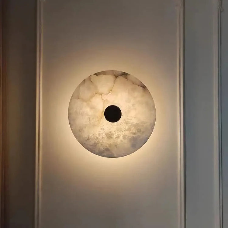 The Morsale Witney Copper & Marble Wall Sconce casts a warm glow with its marble-like pattern and dark circular center, combining modern style lighting with minimalist elegance.