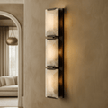 Brookhill Calcite Sconce with three vertical natural calcite prisms on an iron frame, glowing softly on a beige wall.