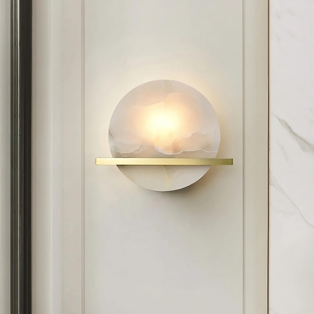 The Morsale.com Natural Marble Wall Light Sconce with a spherical, frosted glass shade diffuses warm light from its LED light source. Mounted on a vertical panel with a horizontal brass accent, it adds a sleek touch. The surrounding light-colored wall features subtle veining, enhancing the minimalist design.