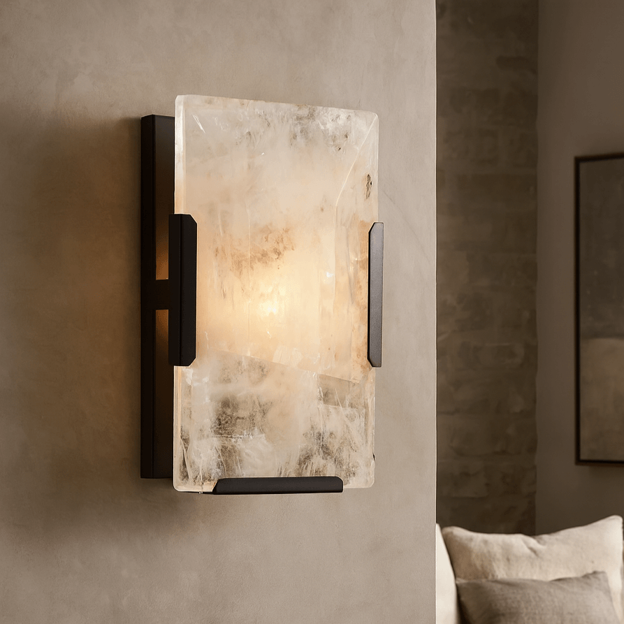 Wall sconce with marble-like finish on a wall in a room with a sofa and framed artwork.