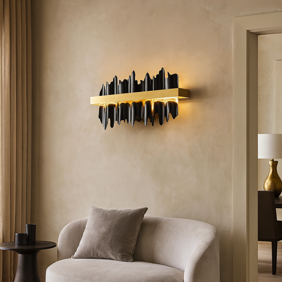 A modern living room features a curved beige sofa, a round dark side table, and the Nera Wall Sconce by Morsale.com illuminating a textured beige wall. A lamp and vase are visible through an open doorway.