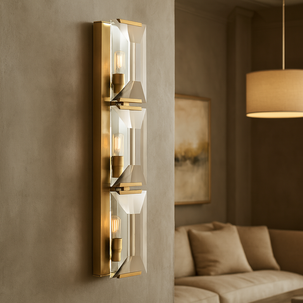 
                  
                    A modern living room showcases a beige sofa, abstract wall art, and the Brookhill Crystal Wall Sconce by Morsale.com, featuring three exposed bulbs behind glass panels. A round pendant light is suspended from the ceiling.
                  
                