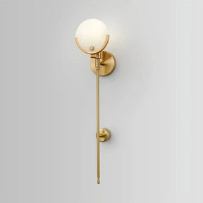 A modern, gold wall sconce is mounted on a light gray wall. Featuring a sleek, vertical design with a round, frosted bulb at the top and an extended rod beneath it, the Natural Marble Wall Light Sconce from Morsale.com adds an elegant and minimalist touch to the decor.