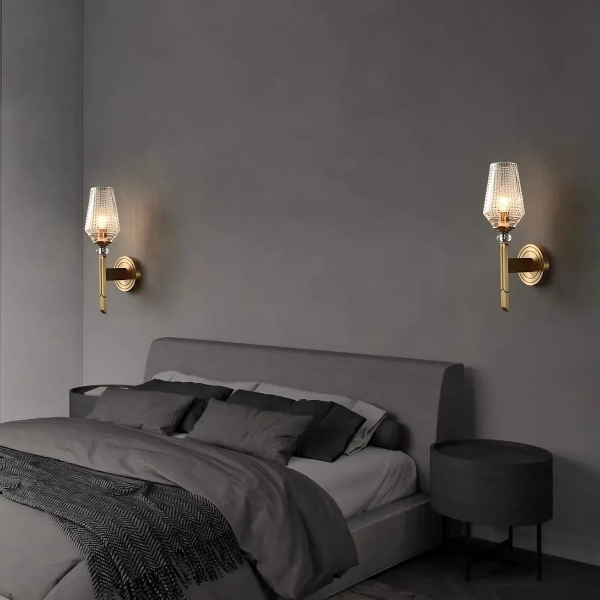 The Palermo Copper & Glass Contemporary Wall Sconce by Morsale features a gold-colored base and a textured glass shade, illuminated with energy-efficient LED light. Crafted from copper, this sconce is mounted on a gray wall, offering a sleek and elegant appearance.