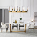 Modern dining room with a marble table, four white and black chairs, minimalist decor, and the Reiss Dining Room Chandelier by Bigman illuminating the space. Features include white paneled walls, neutral tones, two wine bottles, glasses, and a leafy centerpiece.