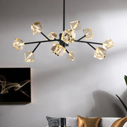 A Morsale.com Diamante Crystal Ceiling Light Fixture, featuring black branches and geometric, crystal-like lampshades, hangs from the ceiling. The room showcases a gray wall with abstract art and a sofa adorned with gray and gold cushions below.